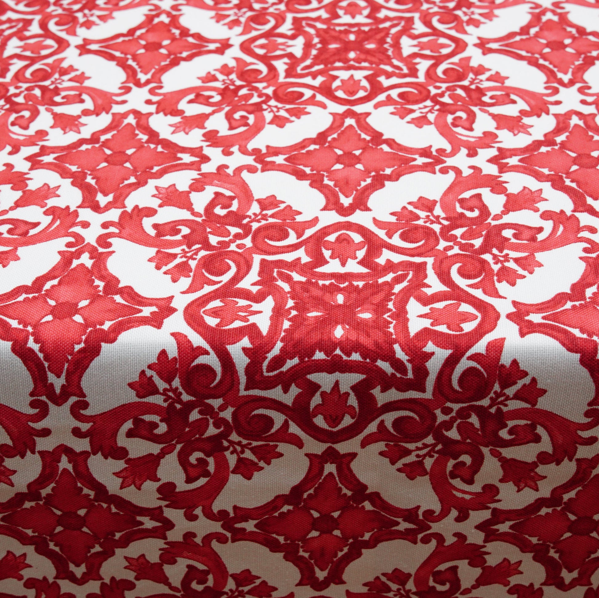 Close-up of a red and white damask tablecloth featuring an ornate ornamental pattern and woven texture