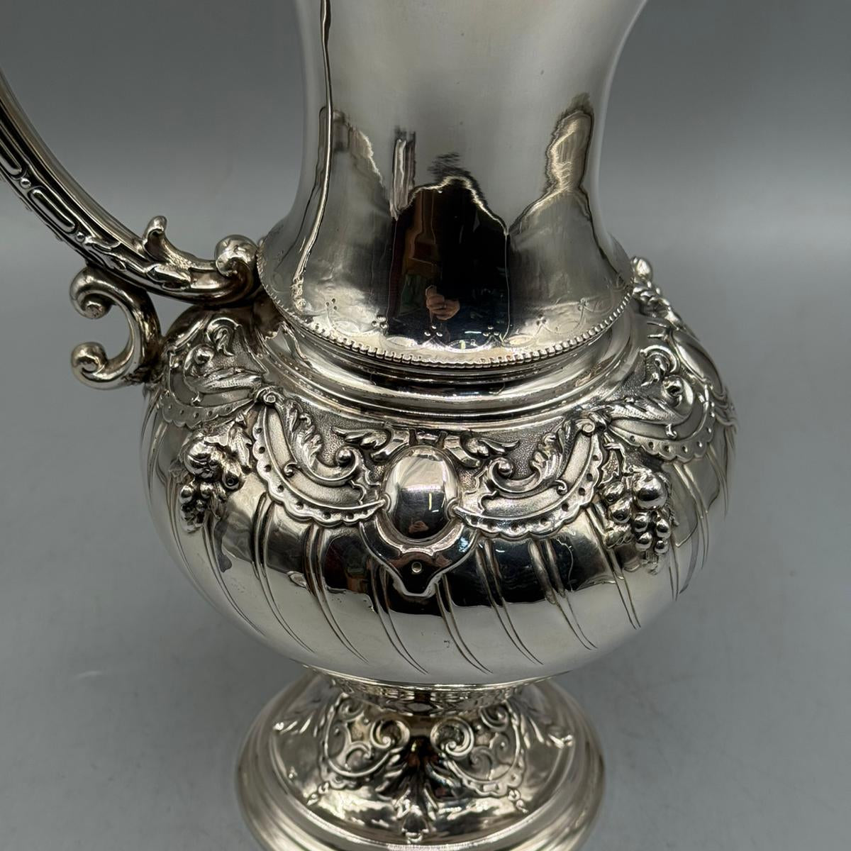 Close up of ornate scroll handle and floral relief on silver ewer by PNR Decor ship from USA