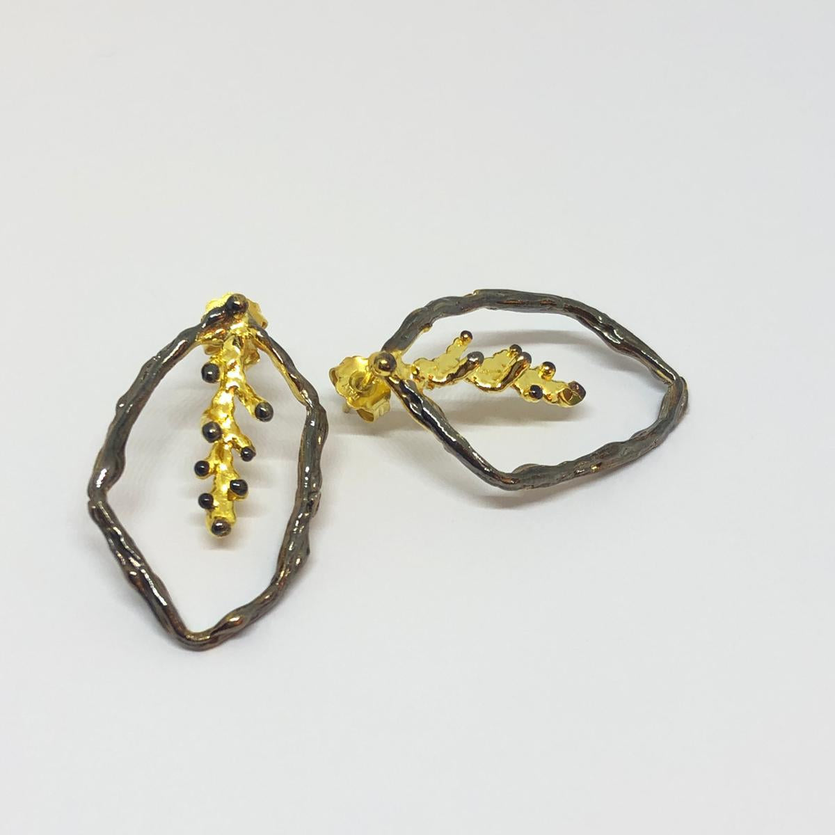 Close-up detail of the textured organic surface on the gold-plated and oxidized 925 silver pine branch earrings, showing the intricate nodes and wood grain.