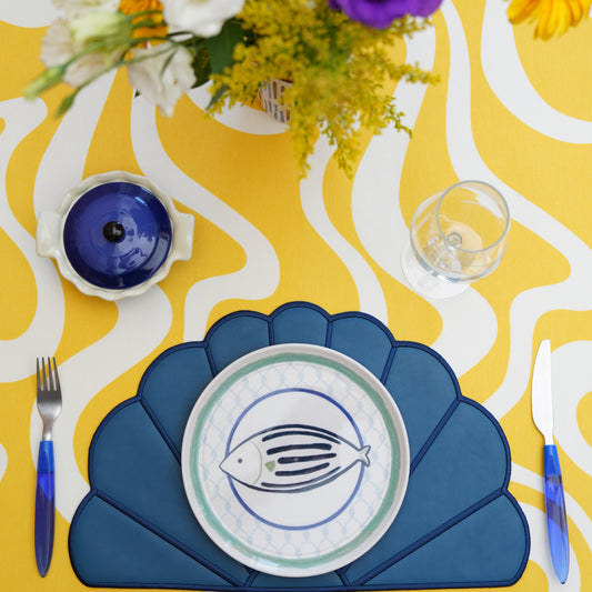 Scalloped round placemat styled on a formal dining table with artisan details