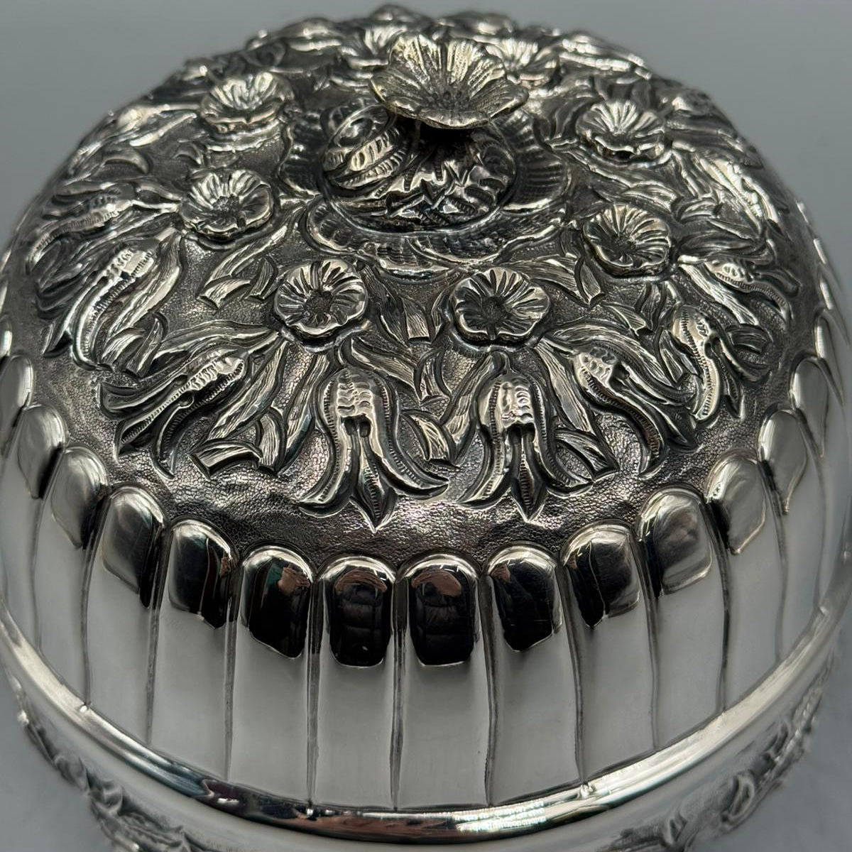 Close-up of the delicate silver blossom handle and detailed hand-engraved floral motifs on the sterling silver lid.
