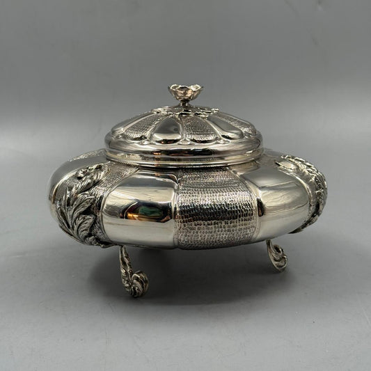 Ornate round silver box with a decorative lid and floral detailing.