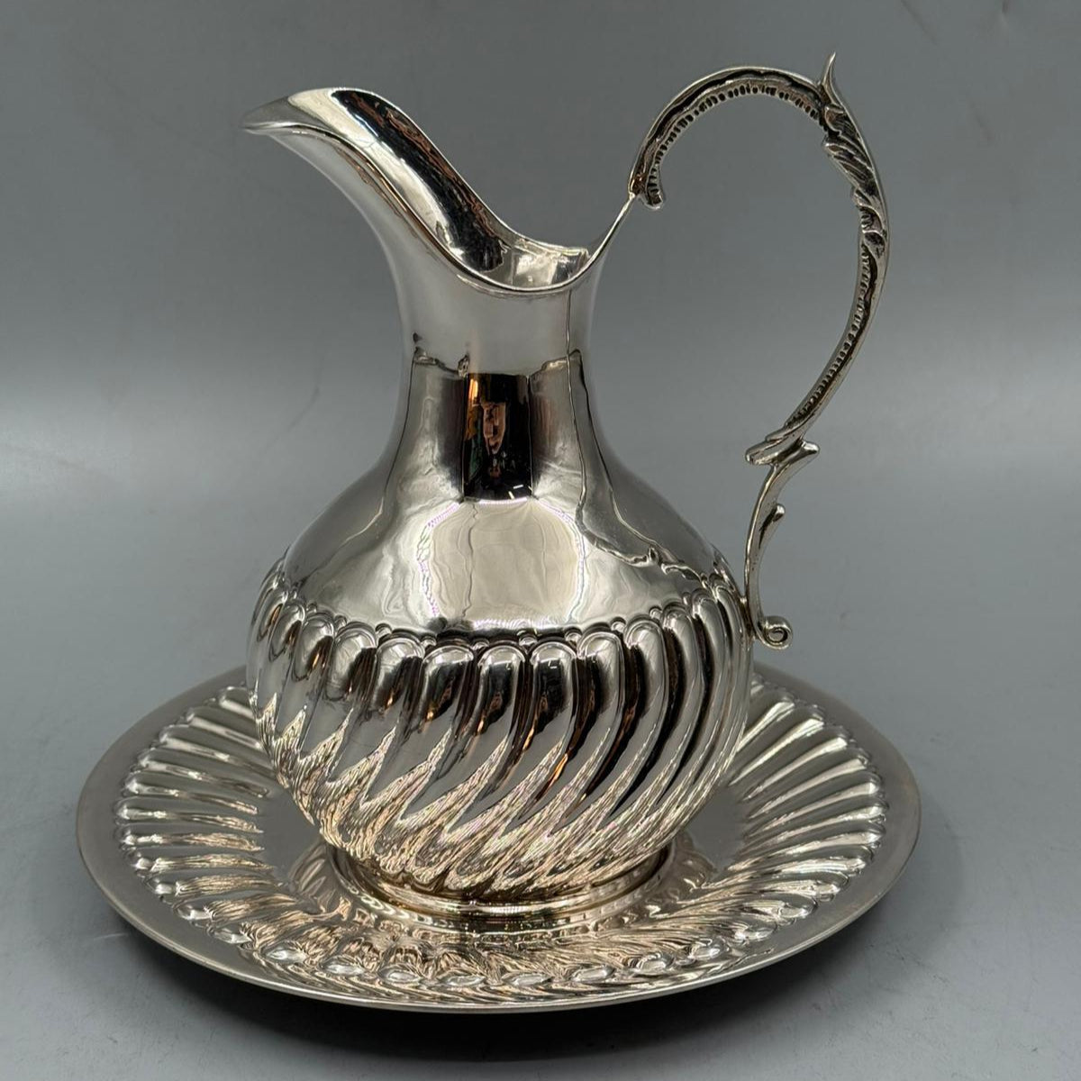 Elegant silver pitcher with decorative handle and matching plate, vintage serving set