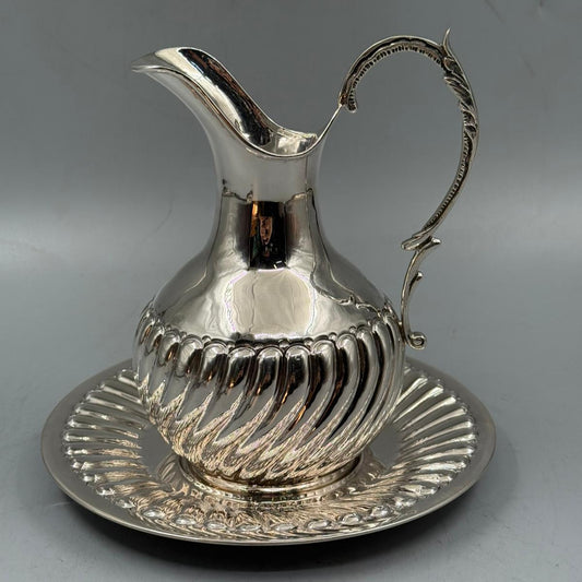 Elegant silver pitcher with decorative handle and matching plate, vintage serving set