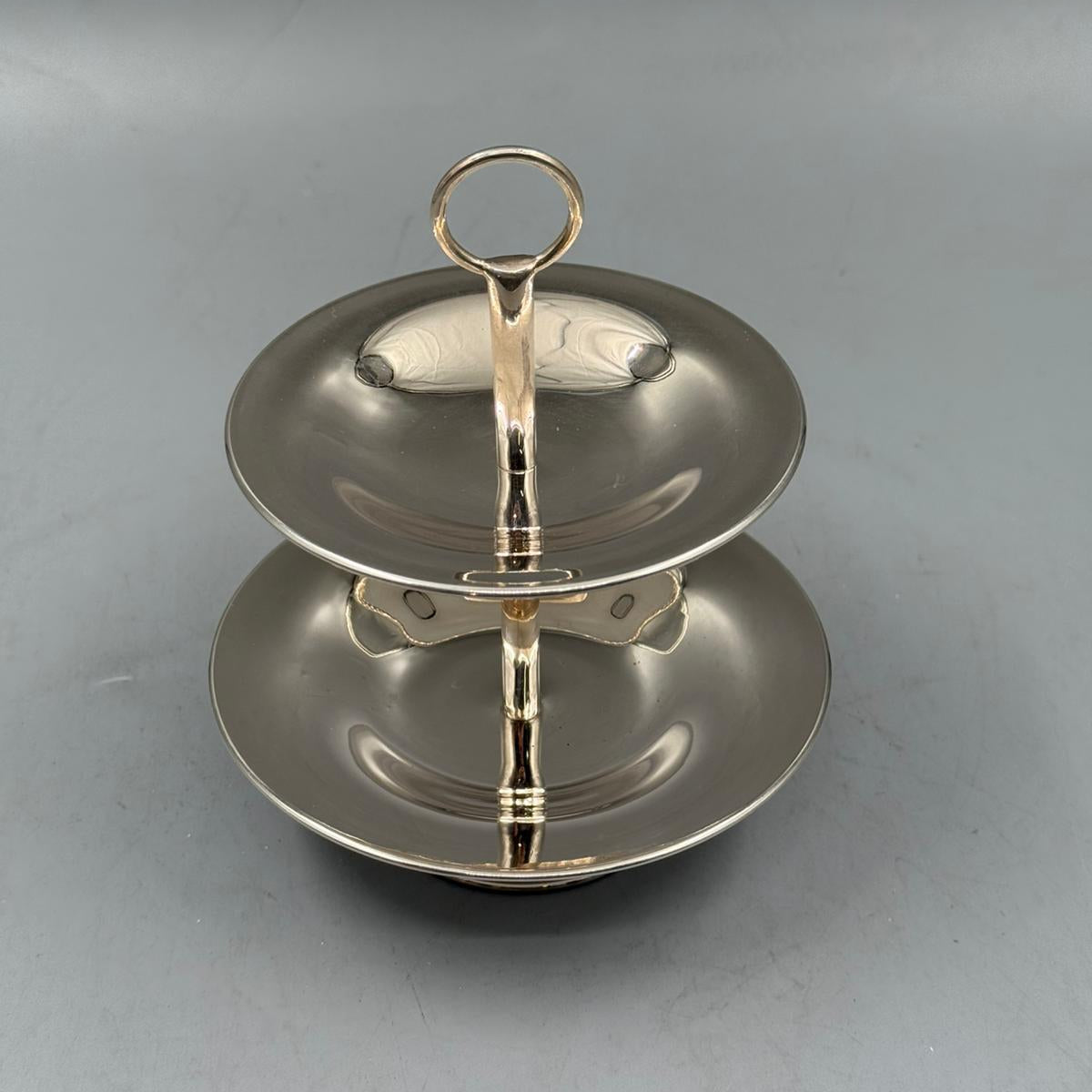 Polished silver two tier fruit stand with handle, ideal for serving apples, grapes, and desserts