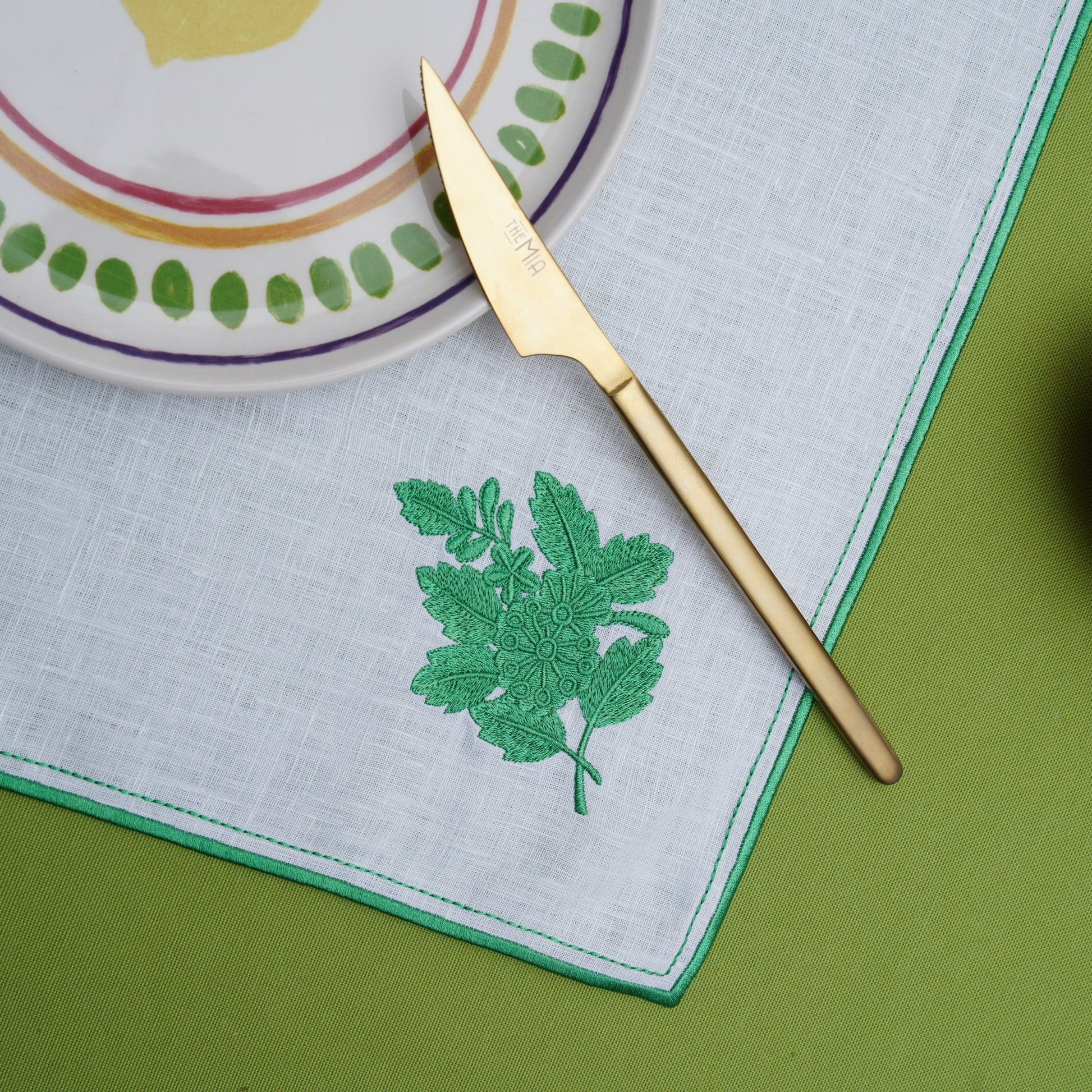 Table setup featuring a white square placemat with botanical embroidery