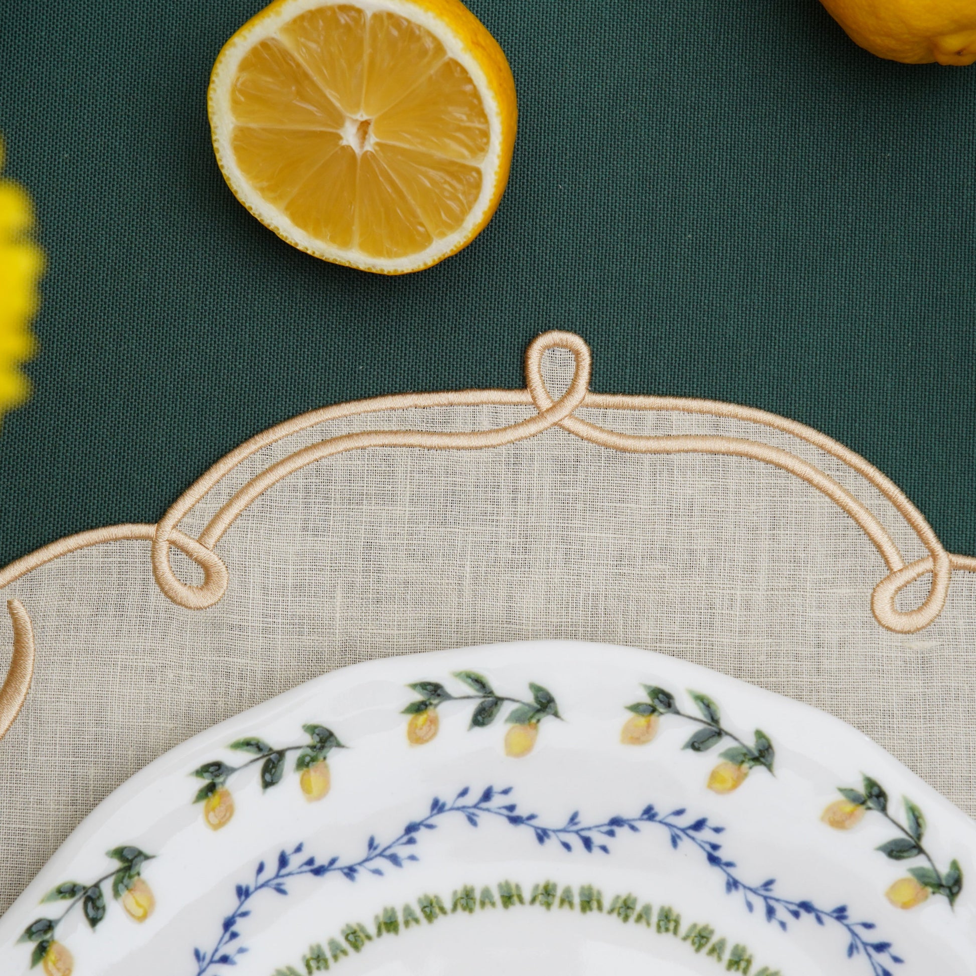 Close-up of ivory square placemat with metallic gold embroidery