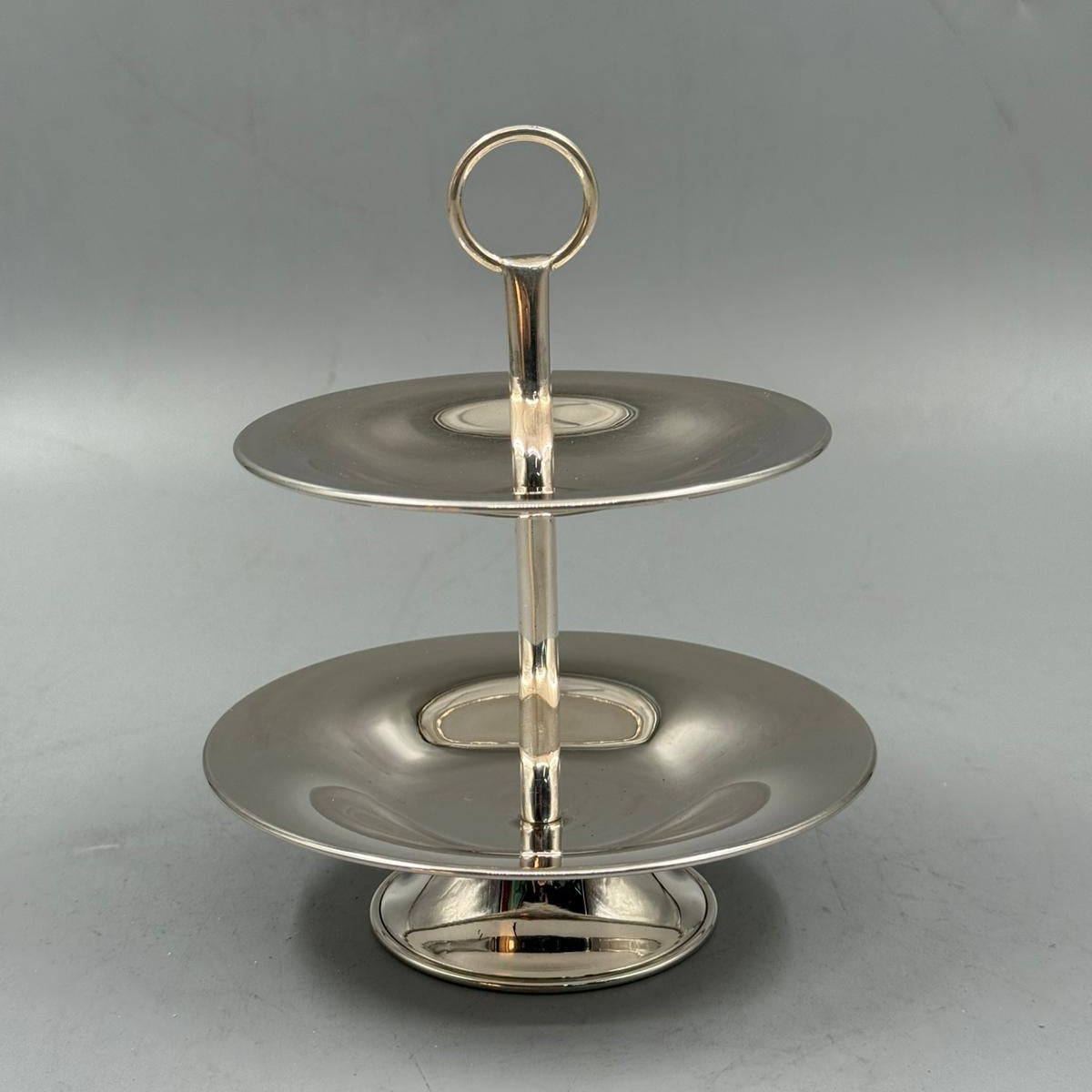 Two tier polished metal dessert stand with shiny surface, great for cakes and sweets