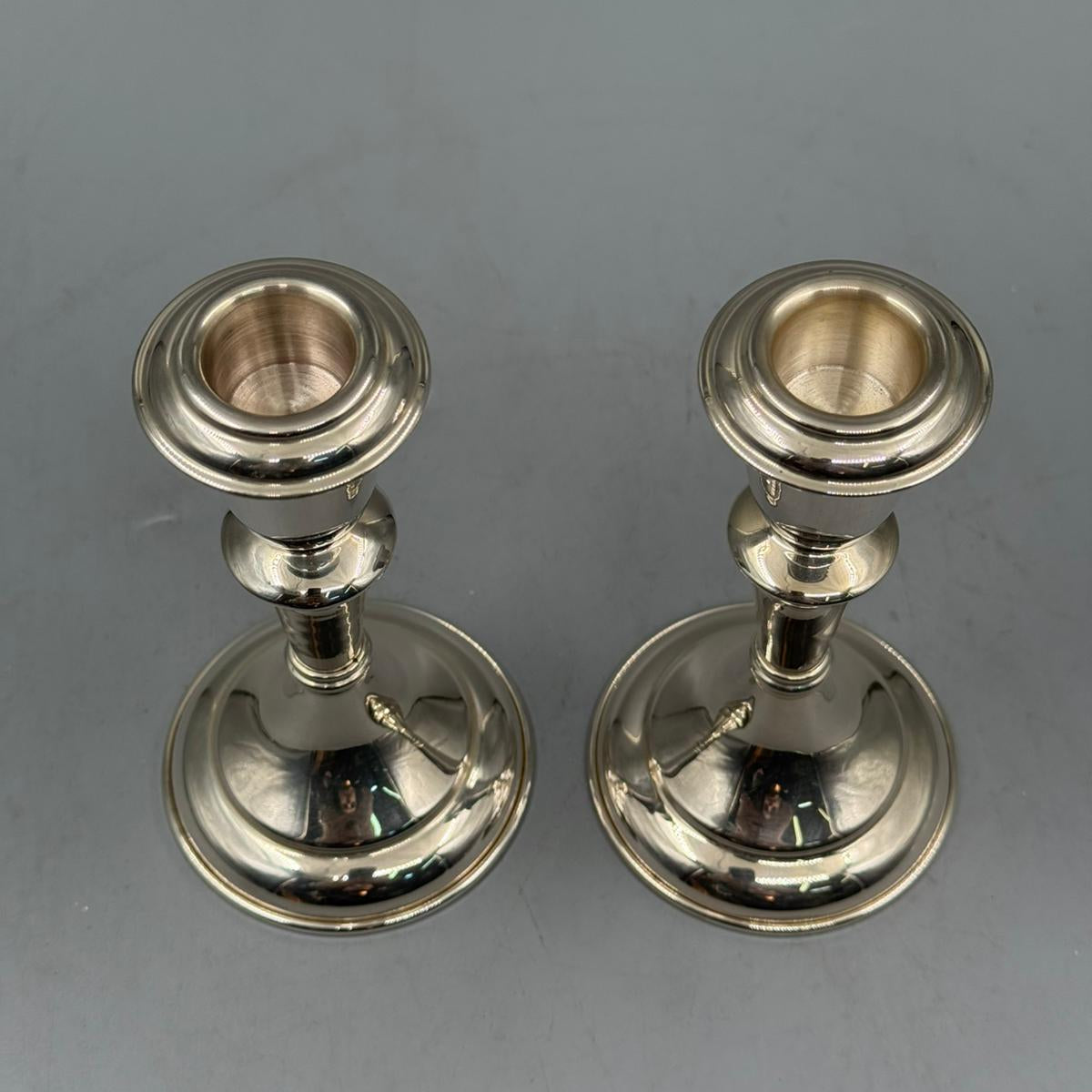 Front view of two vintage silver candle holders with smooth design and rounded bases.