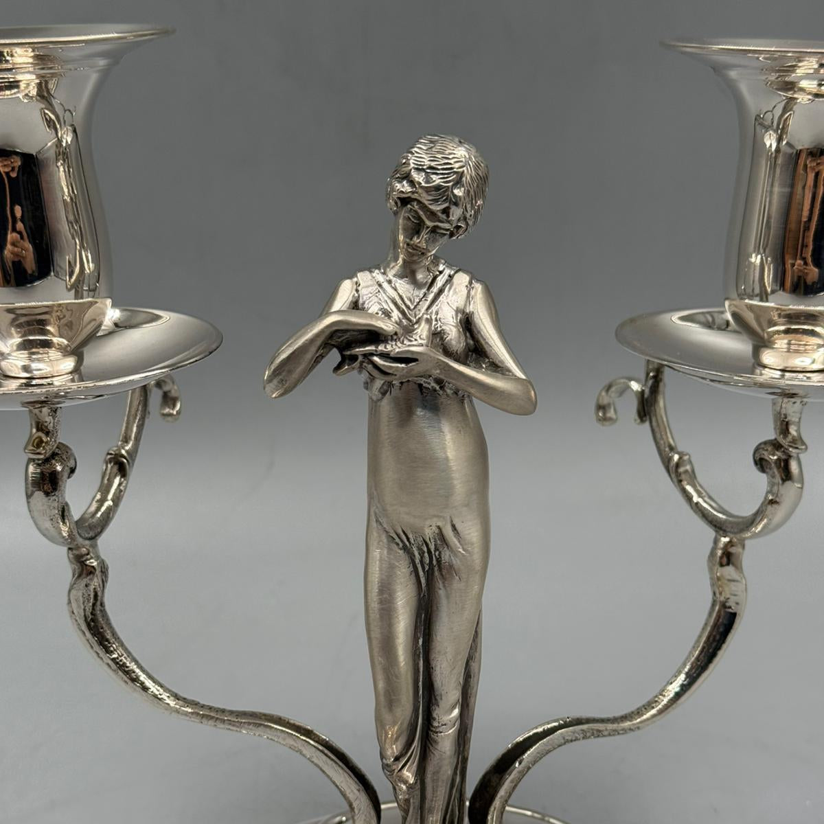 Vintage silver candlestick with a graceful woman statue and two curved candle holders.
