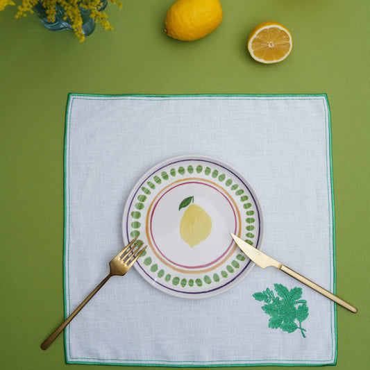 Square linen placemat with delicate leaf embroidery on a styled table